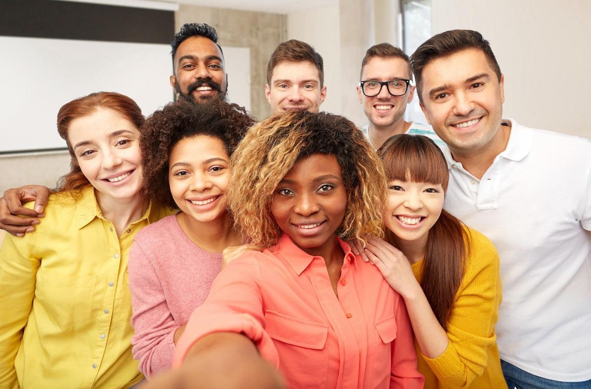 A group of eight diverse future Connecticut teachers gather for a group selfie. The person closest to the front holds out the camera in front of her to take the picture.