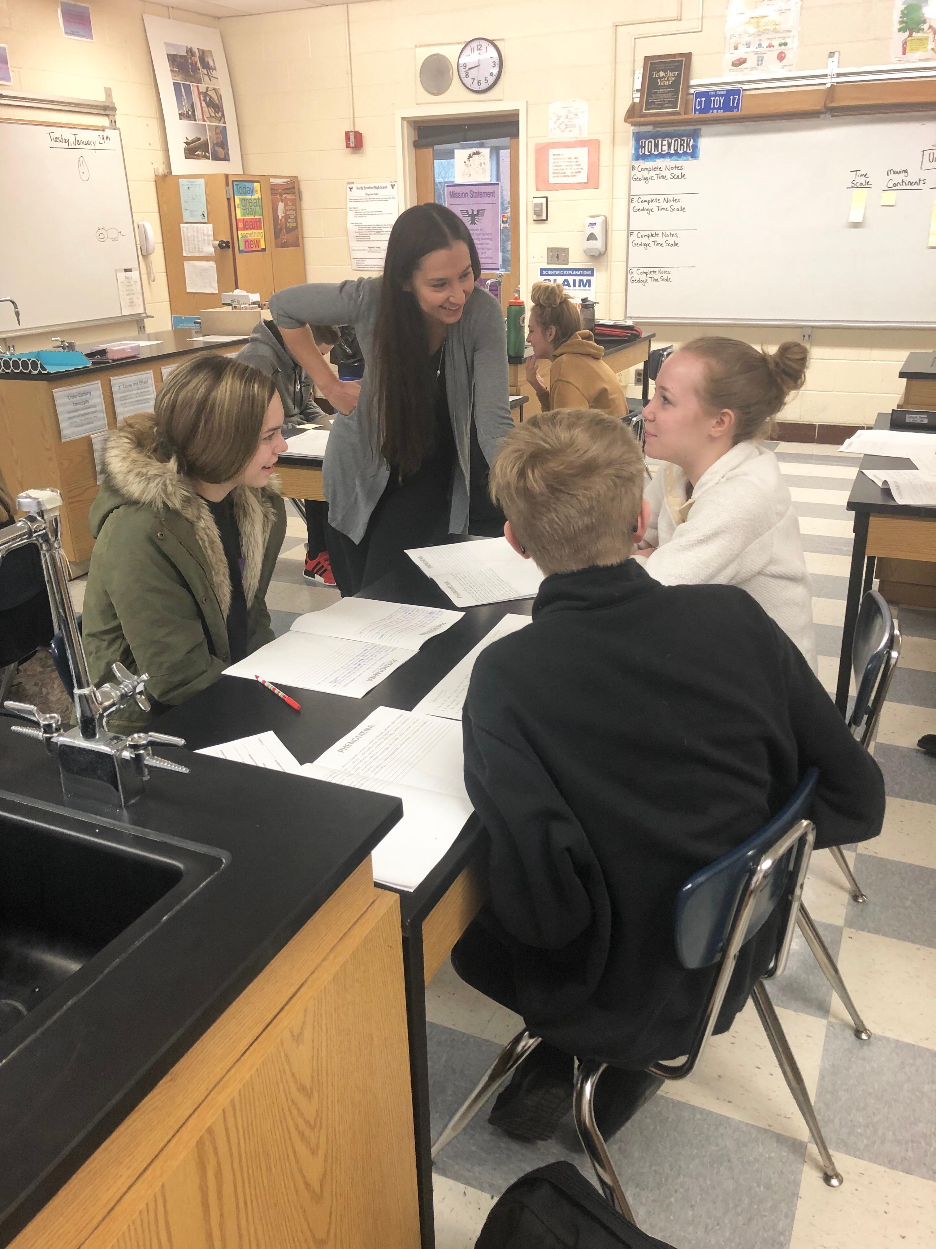 Science teacher Lauren Danner talks with her students at their desks