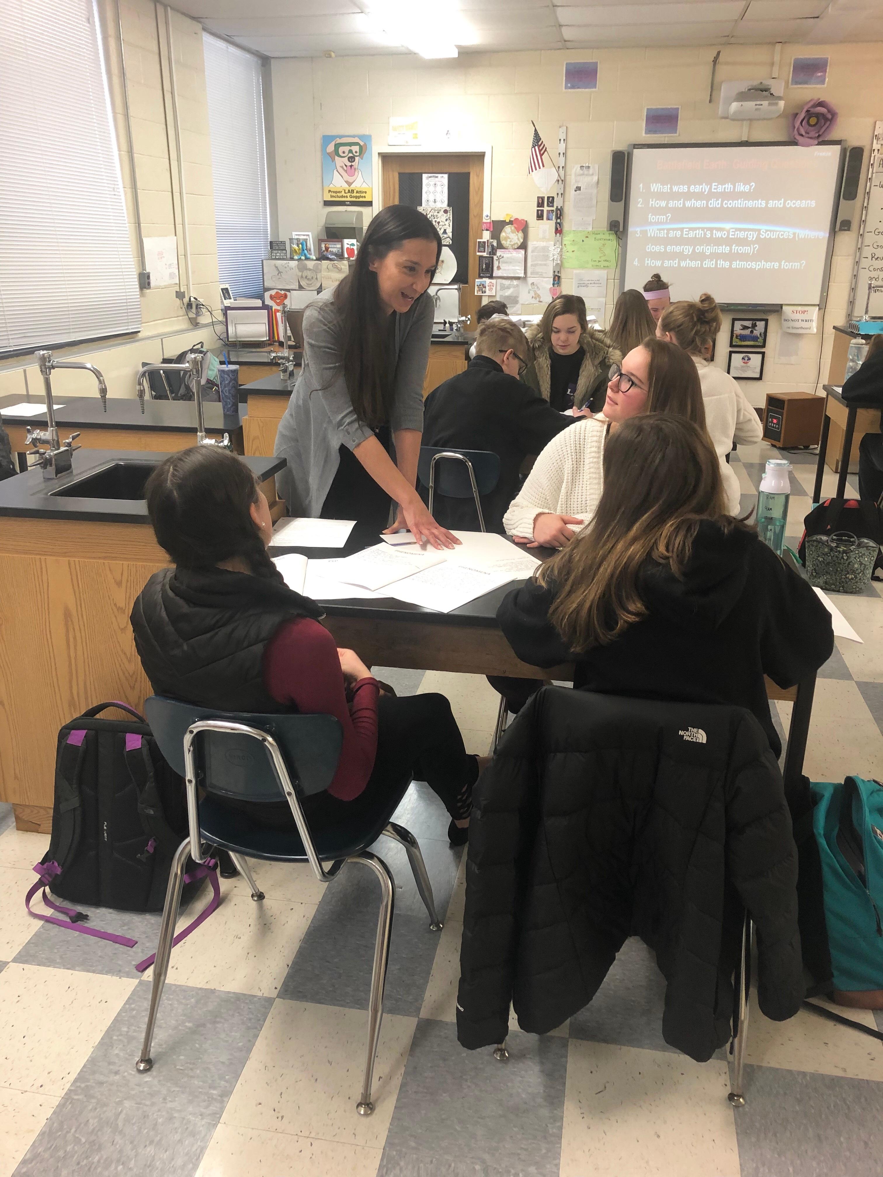 Science teacher Lauren Danner talks to three female students