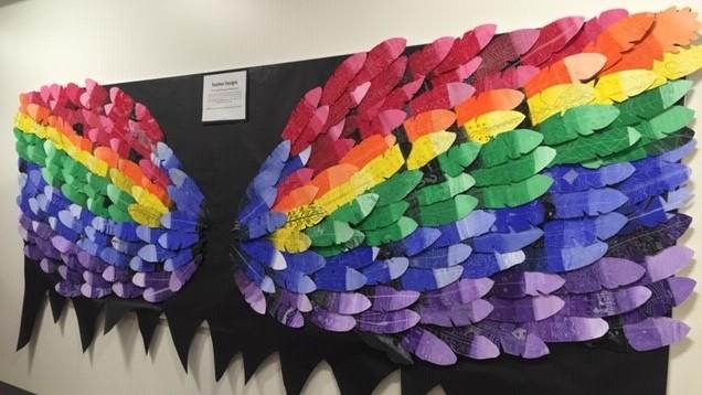 art installation with wings made of rainbow colored feathers