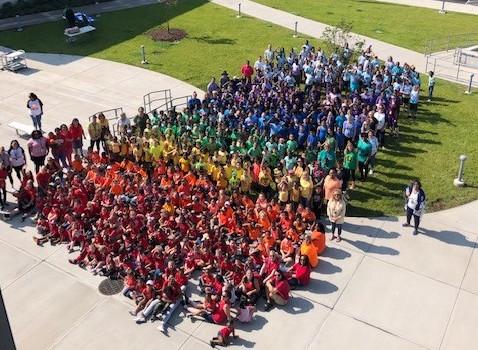 Crowd of students in colorful shirts standing in rainbow order