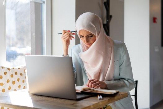 A Muslim woman studies for her Connecticut subject area assessments at her laptop